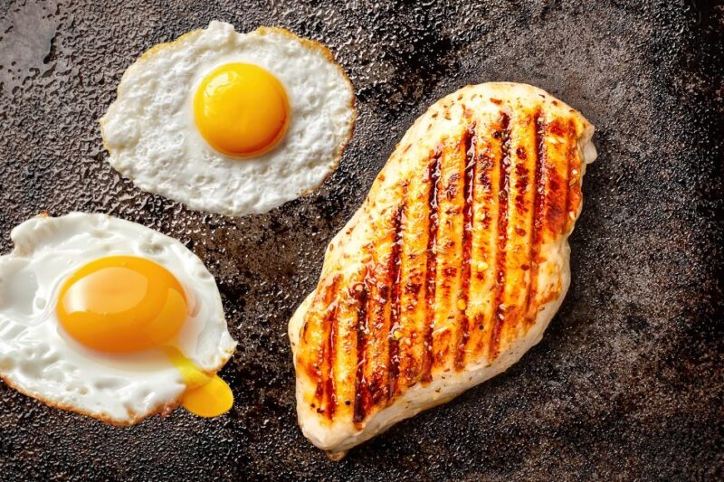 Fried eggs and chicken breast cooking.